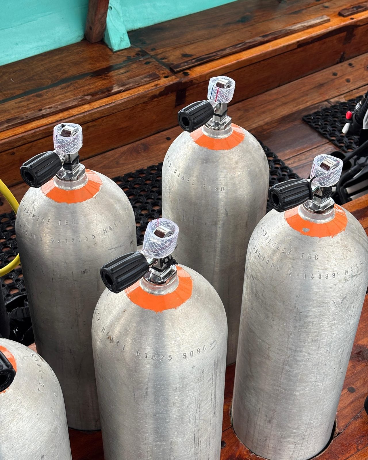 Scuba tanks lined up on the wooden deck of the Moana boat
