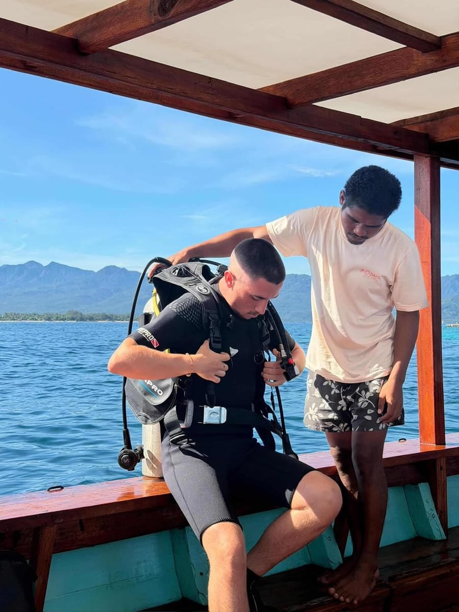 A Moana instructor helping a student diver gear up on the boat