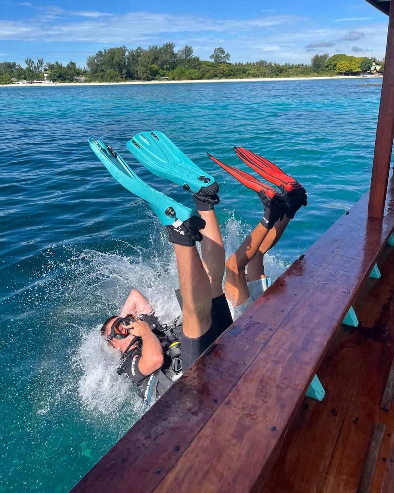 Two divers rolling backwards off the Moana boat into turquoise water
